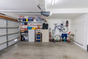 Organized clean residential two car garage with tools, file cabinets and sports equipment without garage door insulation installed.