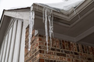 photo looking upwad at roof and ice dams forming in gutter with ice hanging down